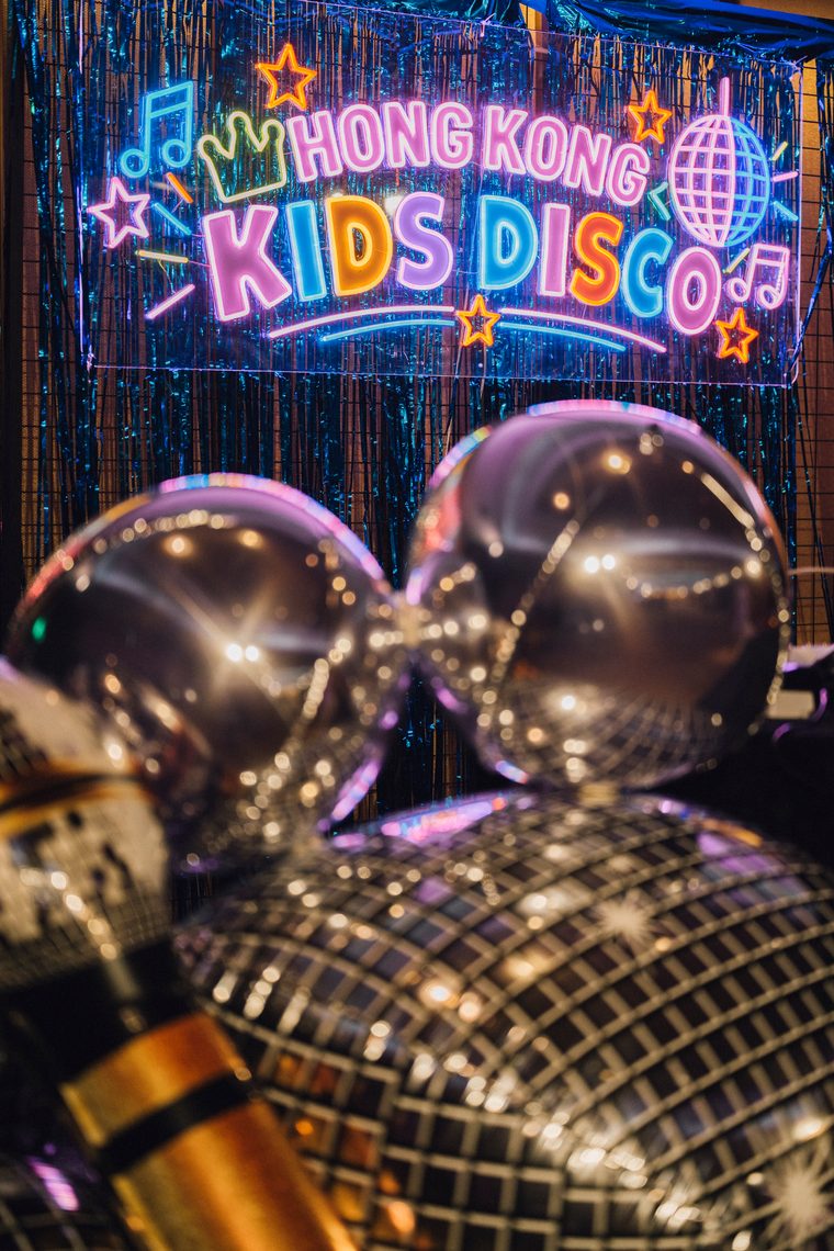 Reflective disco balls and balloons in front of the Kids Disco sign